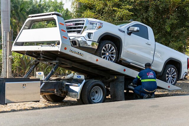 Flatbed tow truck loading a vehicle for transport to the shop